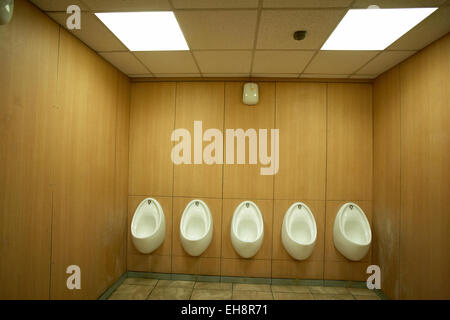 Five white urinals in a men`s toilet UK Stock Photo